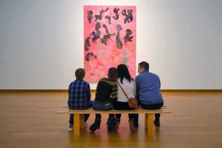 familie op een bankje voor kunstwerk in een museum